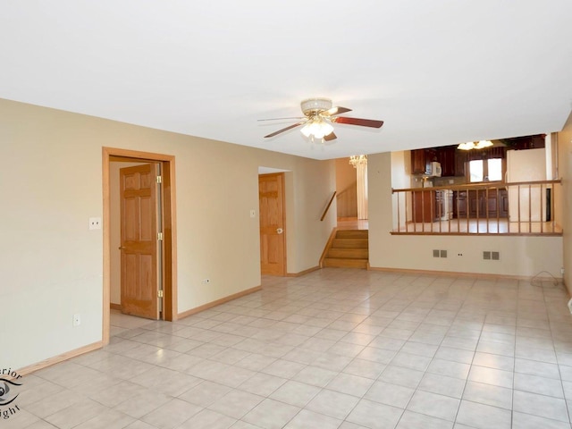 unfurnished living room with visible vents, ceiling fan with notable chandelier, light tile patterned floors, baseboards, and stairs