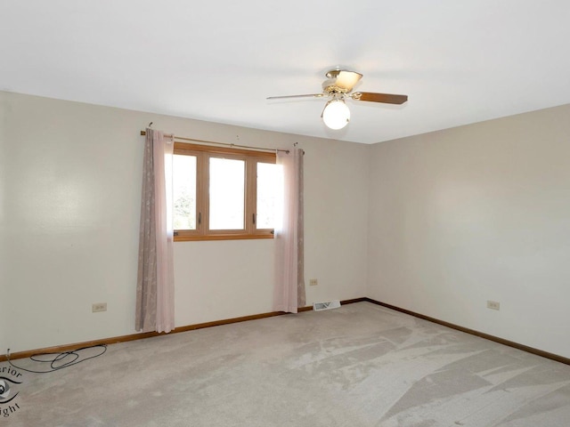 spare room featuring a ceiling fan, baseboards, visible vents, and light carpet