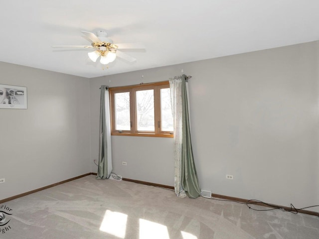 spare room with baseboards, light carpet, and ceiling fan