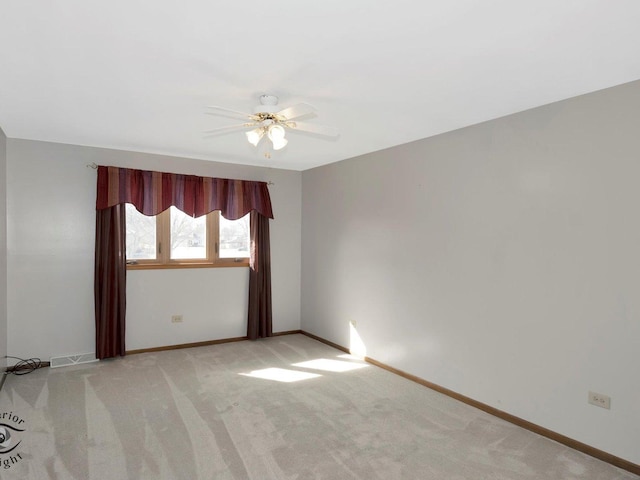 spare room with light carpet, visible vents, ceiling fan, and baseboards