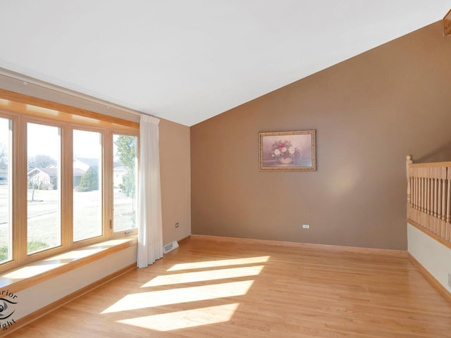 unfurnished room with visible vents, lofted ceiling, baseboards, and light wood-style flooring