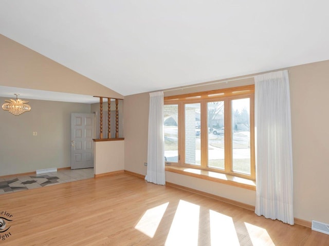 unfurnished living room featuring lofted ceiling, light wood-type flooring, visible vents, and a chandelier