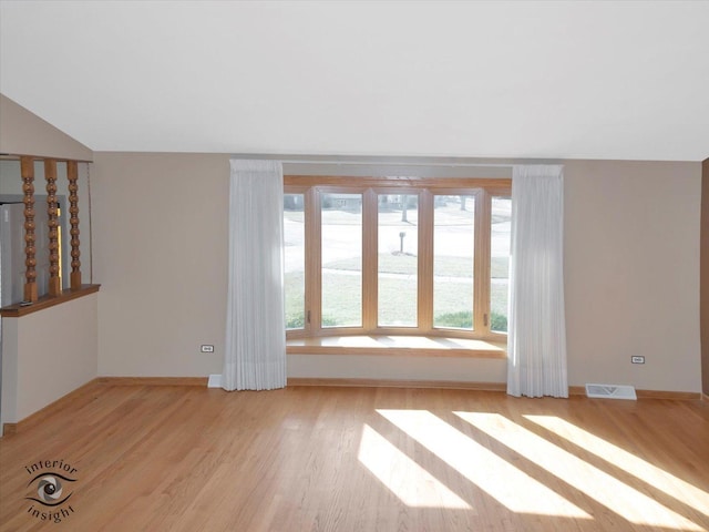 spare room featuring visible vents, baseboards, vaulted ceiling, and light wood finished floors