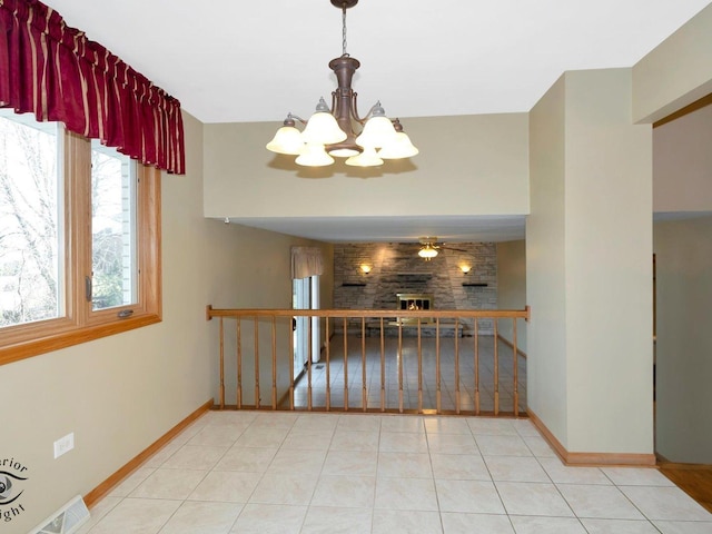 interior space featuring baseboards, a notable chandelier, a fireplace, and tile patterned flooring