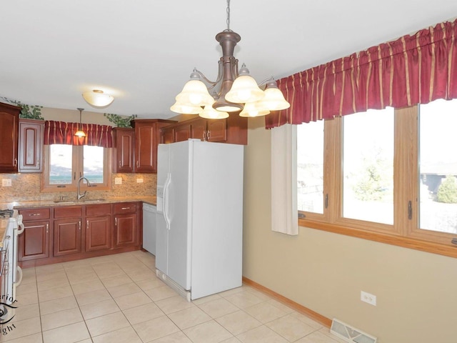 kitchen featuring tasteful backsplash, visible vents, a chandelier, white refrigerator with ice dispenser, and a sink