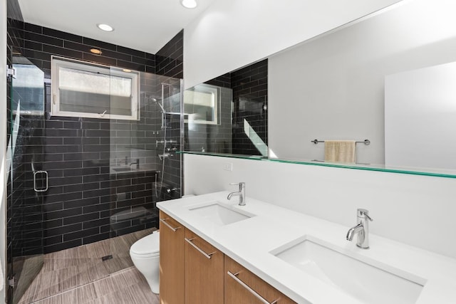 bathroom featuring a shower stall, toilet, double vanity, and a sink