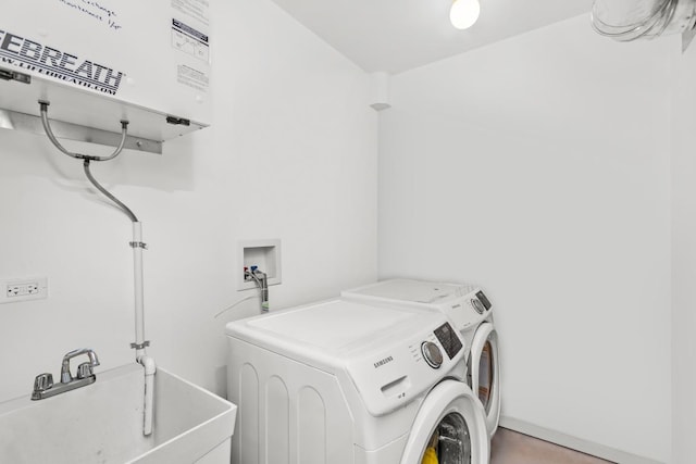 washroom with a sink, water heater, laundry area, and washing machine and clothes dryer