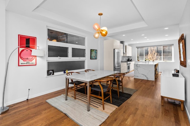 dining room with recessed lighting, baseboards, a raised ceiling, and wood finished floors