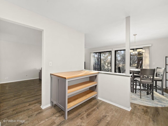 stairway with a notable chandelier, wood finished floors, and baseboards