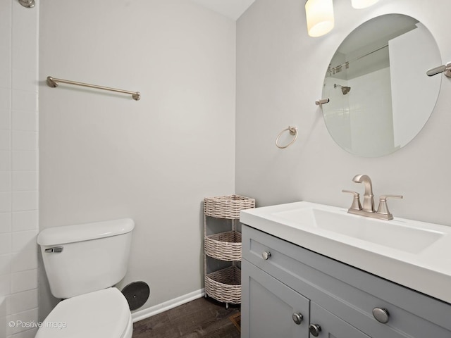 full bathroom with toilet, wood finished floors, baseboards, walk in shower, and vanity