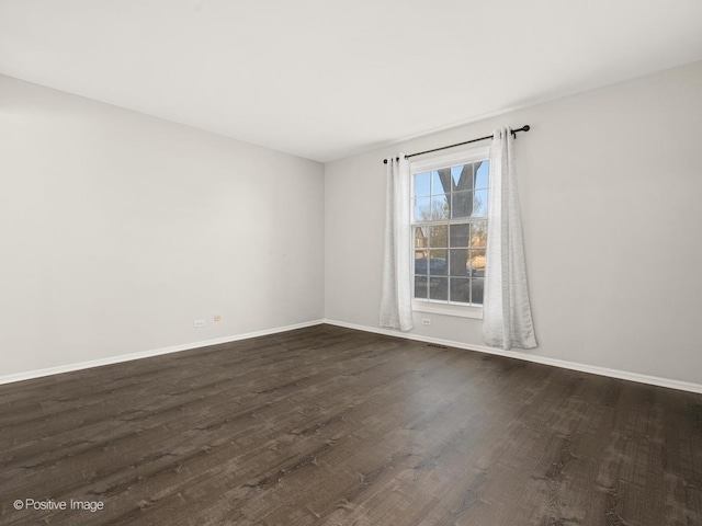 unfurnished room with dark wood finished floors and baseboards