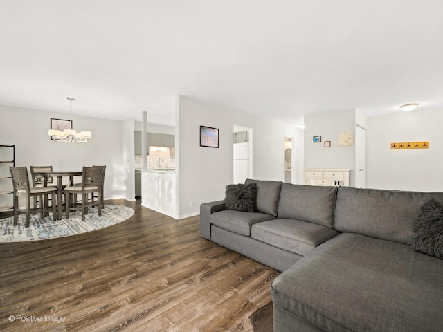 living area with dark wood-type flooring, baseboards, and a chandelier