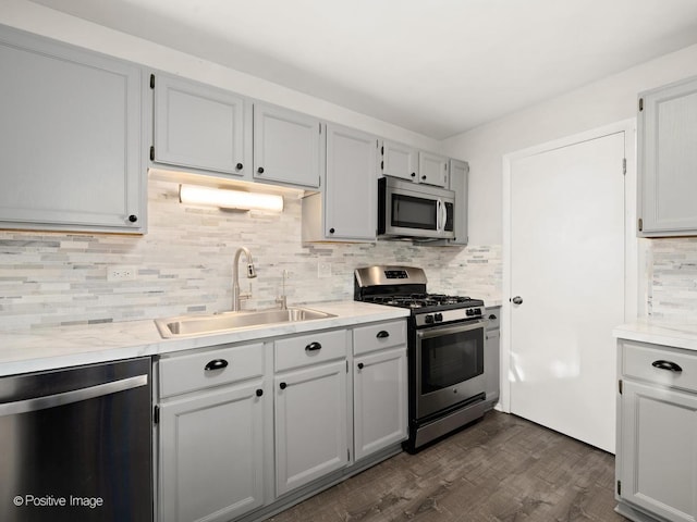 kitchen with tasteful backsplash, appliances with stainless steel finishes, light countertops, and a sink