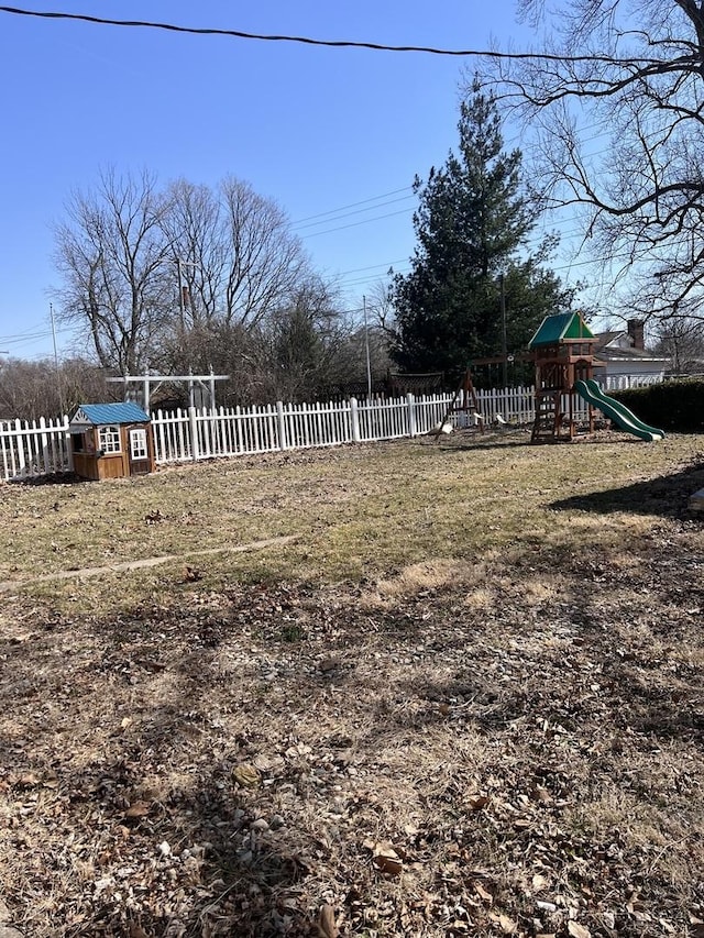 view of yard with a storage unit, fence, an outdoor structure, and a playground