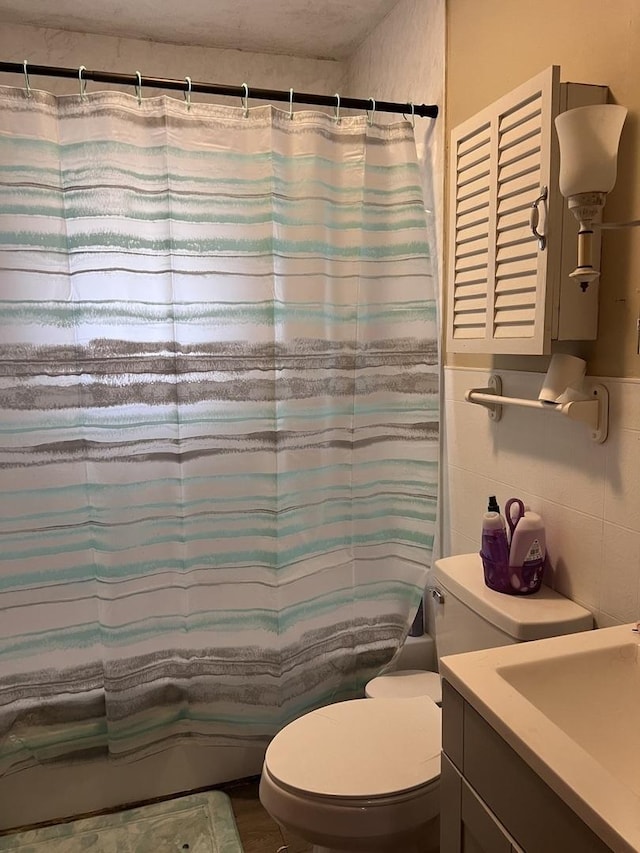 bathroom featuring tile walls, vanity, toilet, and shower / tub combo