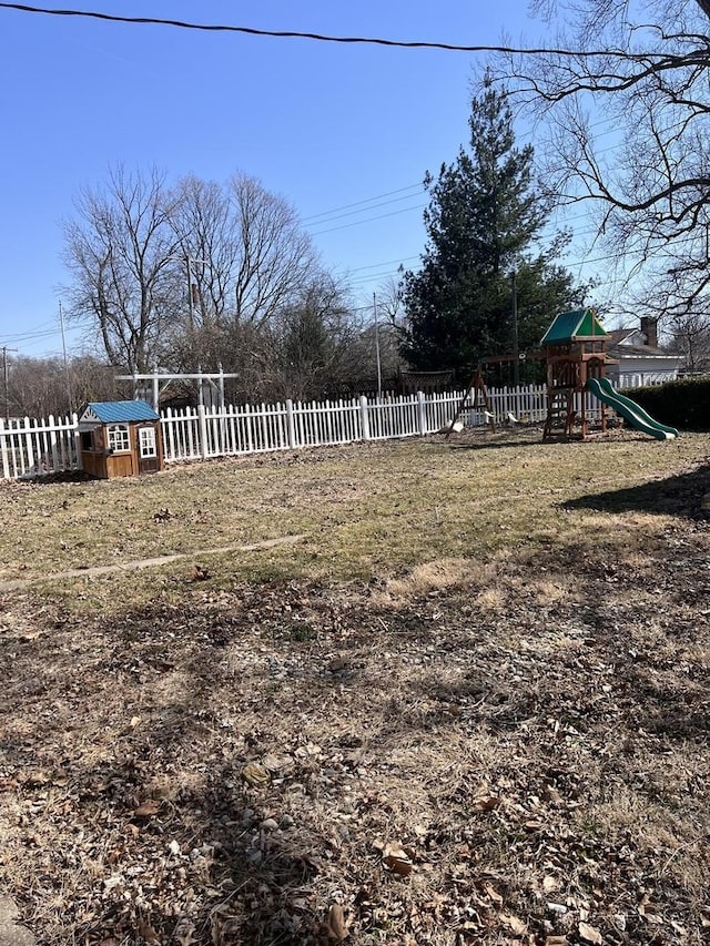 view of yard featuring an outbuilding, a storage shed, a playground, and fence