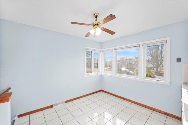 spare room with light tile patterned floors, visible vents, a ceiling fan, and baseboards