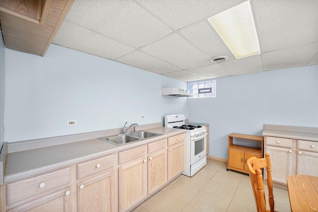 kitchen featuring under cabinet range hood, a sink, light brown cabinets, and white gas range oven