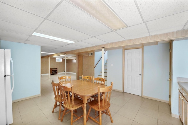 dining area with stairs, light tile patterned flooring, and a drop ceiling