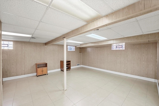 basement with visible vents, baseboards, and a drop ceiling