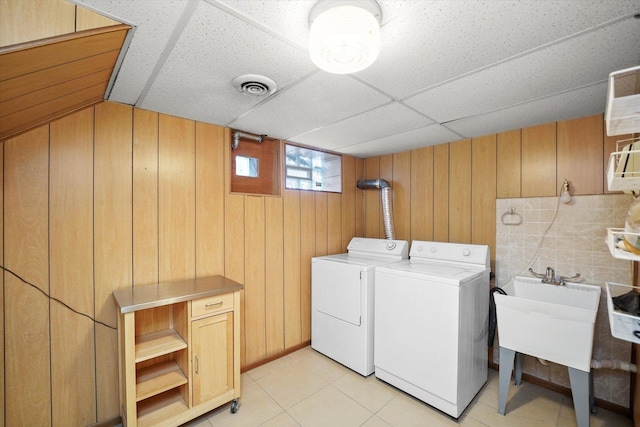 clothes washing area featuring visible vents, wood walls, laundry area, separate washer and dryer, and a sink