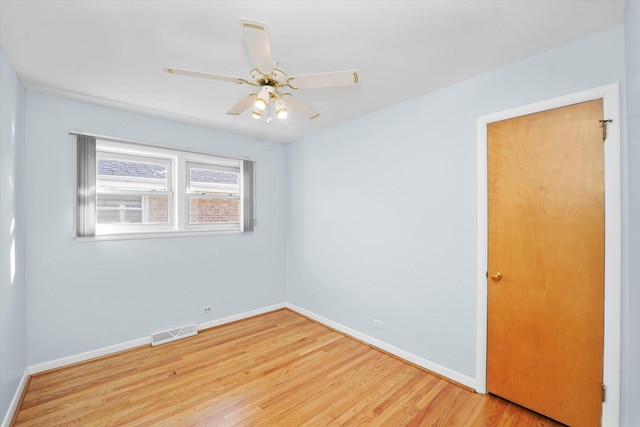 spare room with a ceiling fan, wood finished floors, visible vents, and baseboards