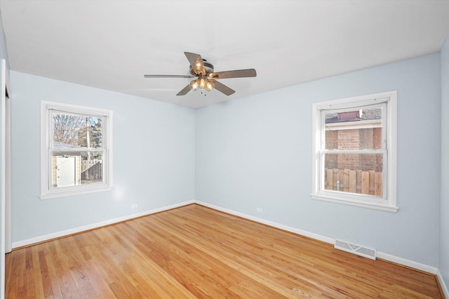 spare room with a ceiling fan, wood finished floors, visible vents, and baseboards