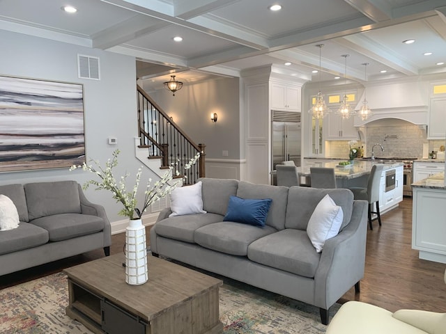 living area with beam ceiling, a notable chandelier, visible vents, and dark wood-style flooring