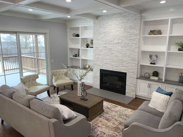 living area featuring beam ceiling, dark wood-type flooring, built in features, recessed lighting, and a stone fireplace