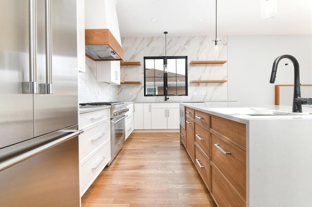 kitchen with light wood-type flooring, premium appliances, decorative backsplash, white cabinetry, and open shelves