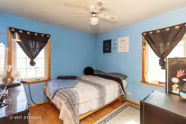 bedroom featuring baseboards, wood finished floors, and a ceiling fan