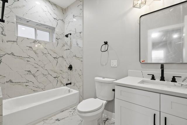 full bathroom with vanity, baseboards, shower / bath combination, toilet, and marble finish floor