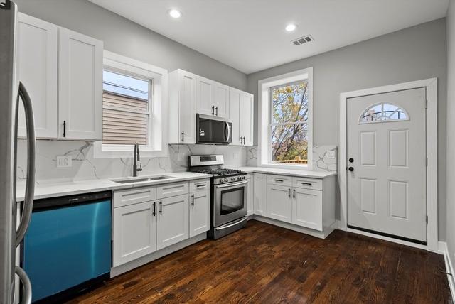 kitchen featuring a sink, stainless steel appliances, backsplash, and white cabinetry