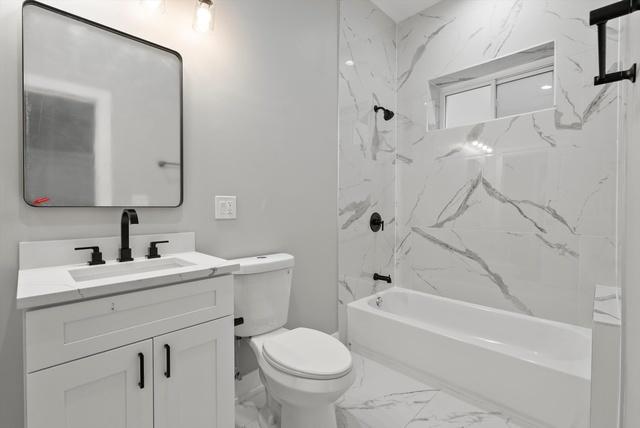 bathroom with vanity, toilet, tub / shower combination, and marble finish floor
