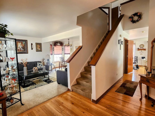 interior space with stairway, an inviting chandelier, baseboards, and wood finished floors