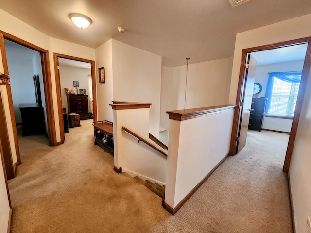 hallway with an upstairs landing, light colored carpet, and baseboards