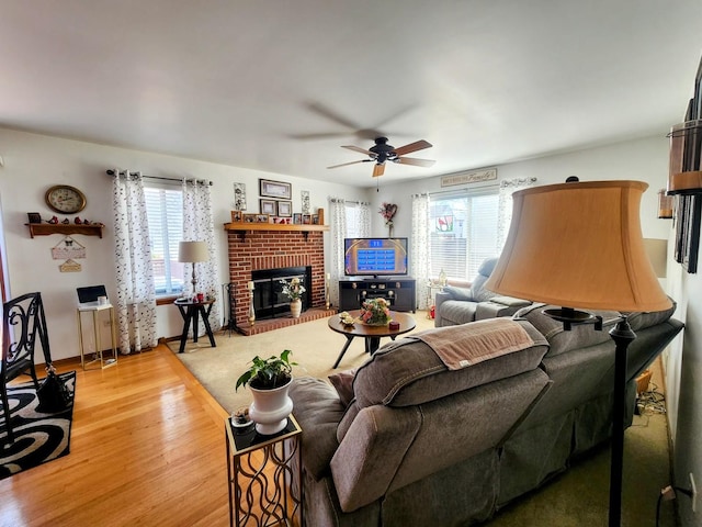 living room featuring a healthy amount of sunlight, a brick fireplace, a ceiling fan, and wood finished floors