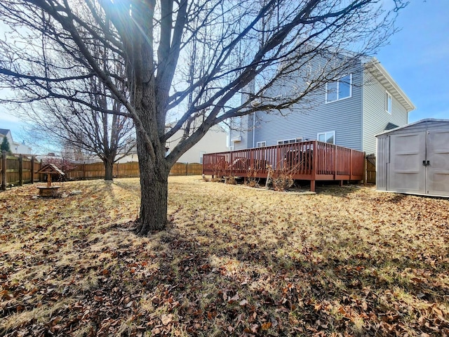 view of yard featuring a deck, an outdoor structure, a fenced backyard, and a shed