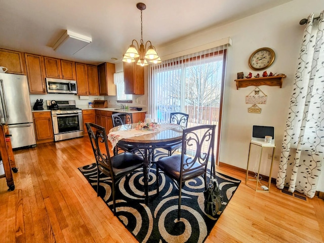 dining area featuring light wood-type flooring, an inviting chandelier, and a healthy amount of sunlight