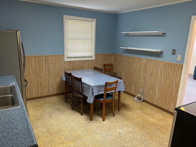 dining area featuring a wainscoted wall, wood walls, and ornamental molding