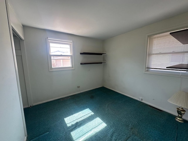 unfurnished bedroom with visible vents, dark colored carpet, and baseboards