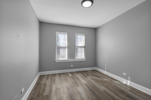 spare room with baseboards and wood finished floors