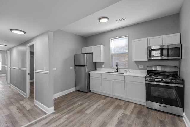 kitchen featuring visible vents, a sink, appliances with stainless steel finishes, white cabinets, and light countertops