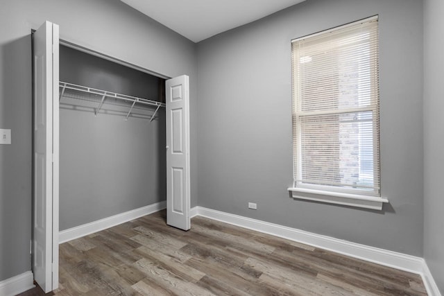 unfurnished bedroom with a closet, baseboards, and wood finished floors