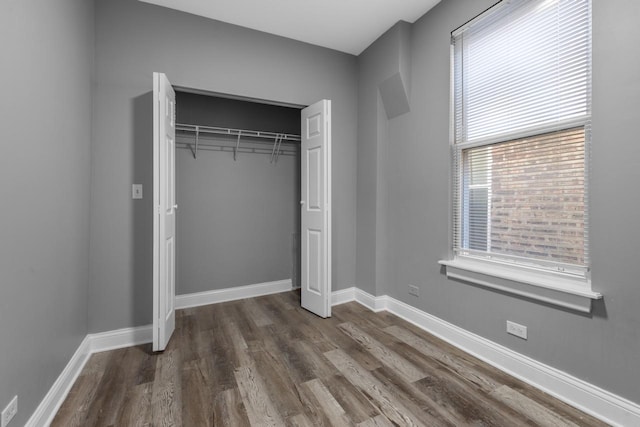 unfurnished bedroom featuring a closet, baseboards, and dark wood-style floors