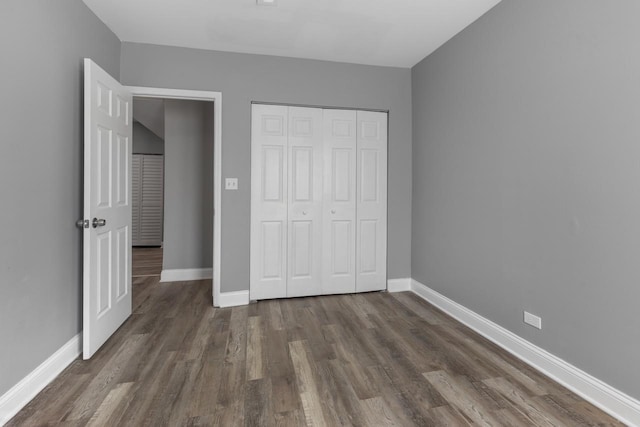 unfurnished bedroom with wood finished floors, baseboards, and a closet