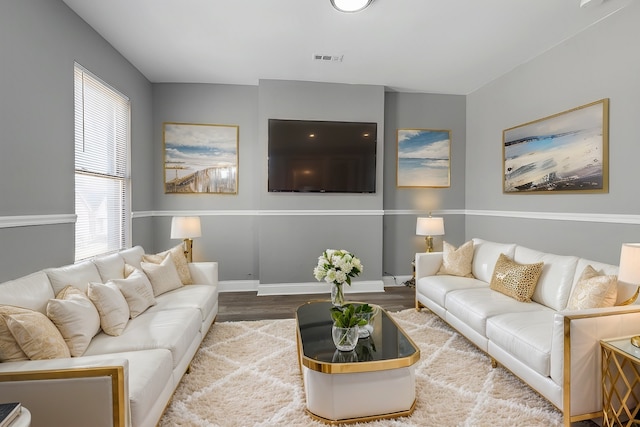 living room featuring visible vents, baseboards, and wood finished floors