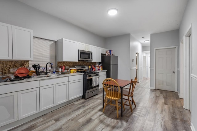 kitchen featuring a sink, tasteful backsplash, appliances with stainless steel finishes, and light wood-style flooring