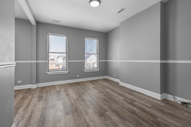 unfurnished room featuring wood finished floors, baseboards, and visible vents