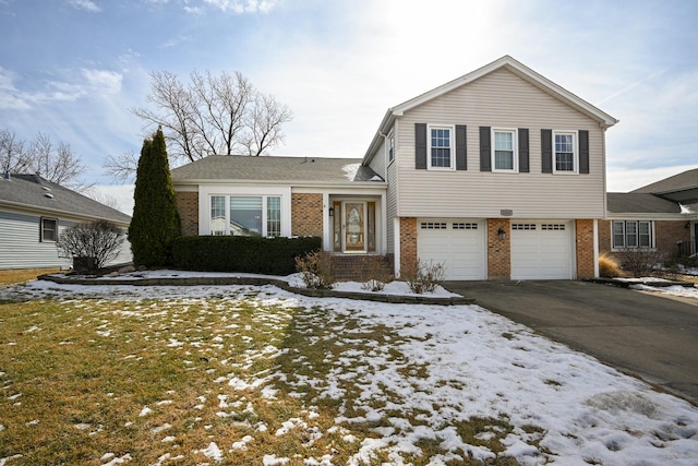 tri-level home featuring aphalt driveway, an attached garage, and brick siding